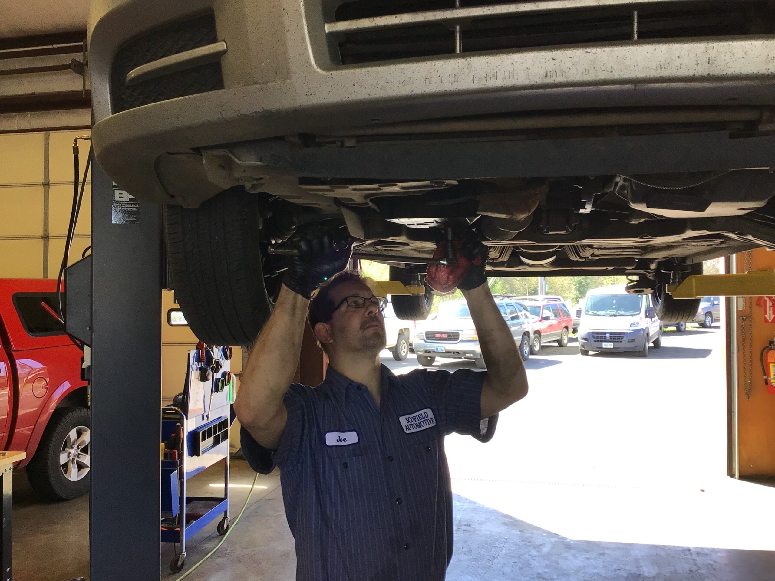 A picture of Joe, one of the mechanics of Scofield Automotive repair in Roseburg working under an elevated car