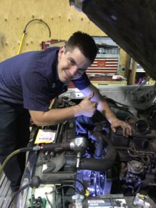 Timothy, a mechanic at Scofield Automotive repair in Roseburg, Or working under the hood of a car