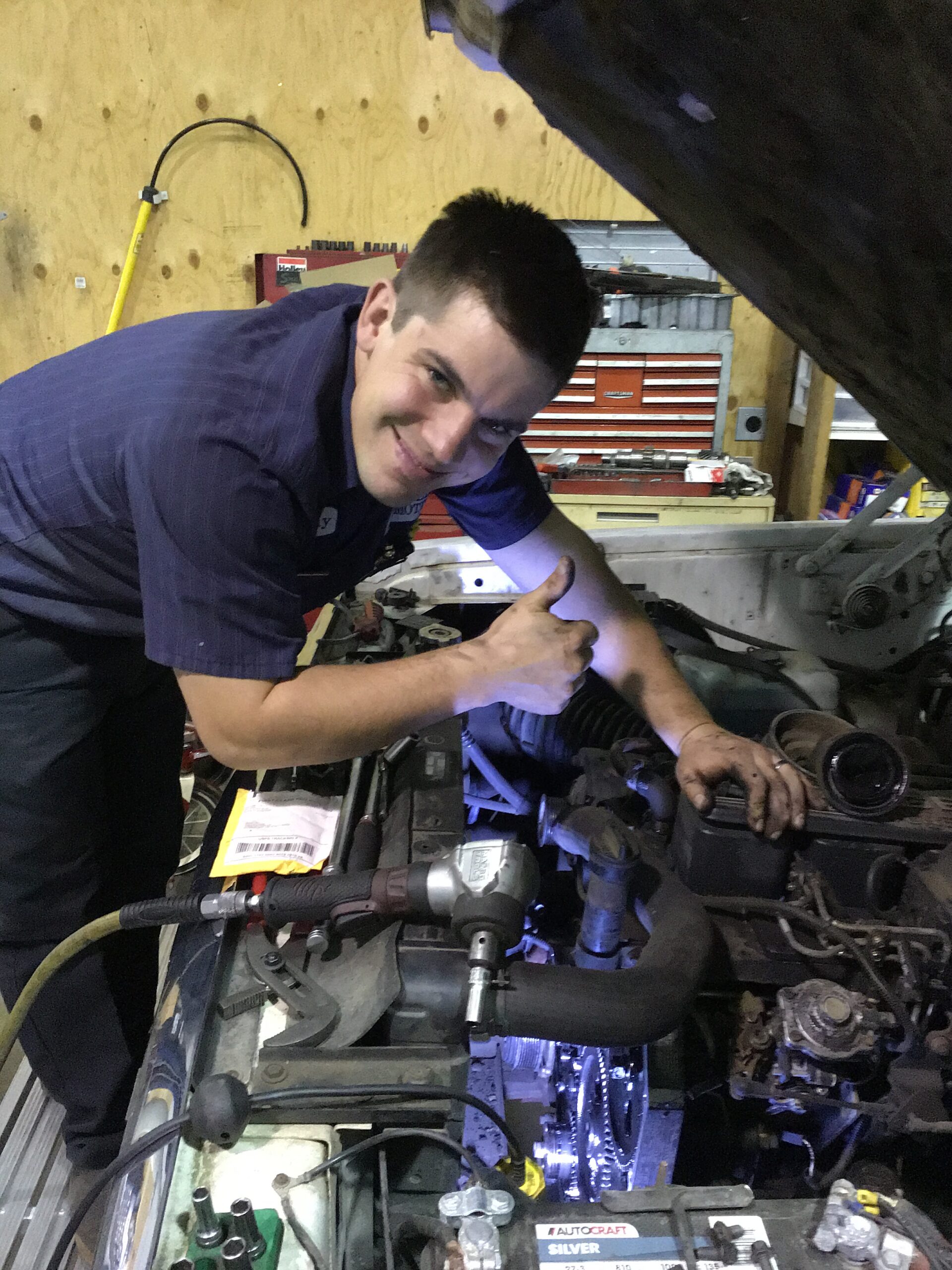Timothy, a mechanic at Scofield Automotive repair in Roseburg, Or working under the hood of a car