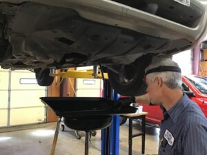 Dylan, one of the technicians at Scofield Automotive repair in Roseburg and Green draining oil